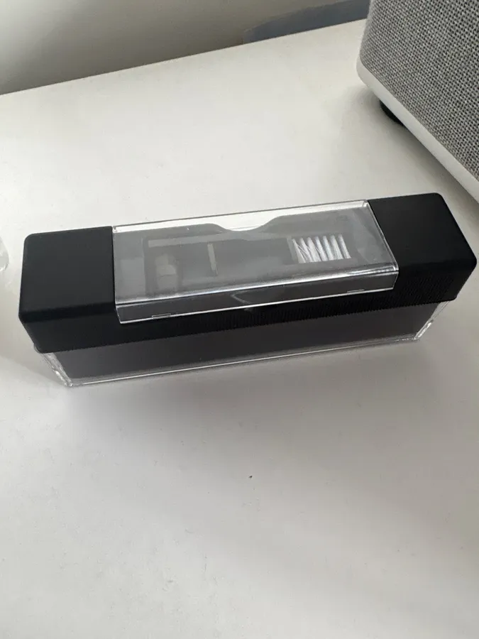 Velvet block with the clear cover slid back, on a white desk beside a fabric-covered speaker
