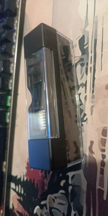 Velvet block held up against a patterned background, the white nylon detail brush visible through the clear cover